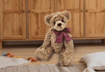 teddy bear sitting in the floor with burgundy bow